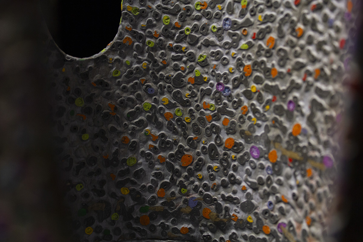 détail de la sculpture, on peut y voir la texture granuleuse et colorée en papier mâché, des motifs géométriques et végétaux