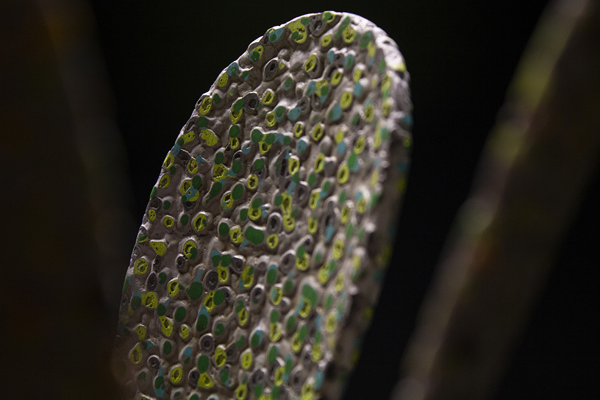 détail de la sculpture, on peut y voir la texture granuleuse et colorée en papier mâché, des motifs géométriques et végétaux